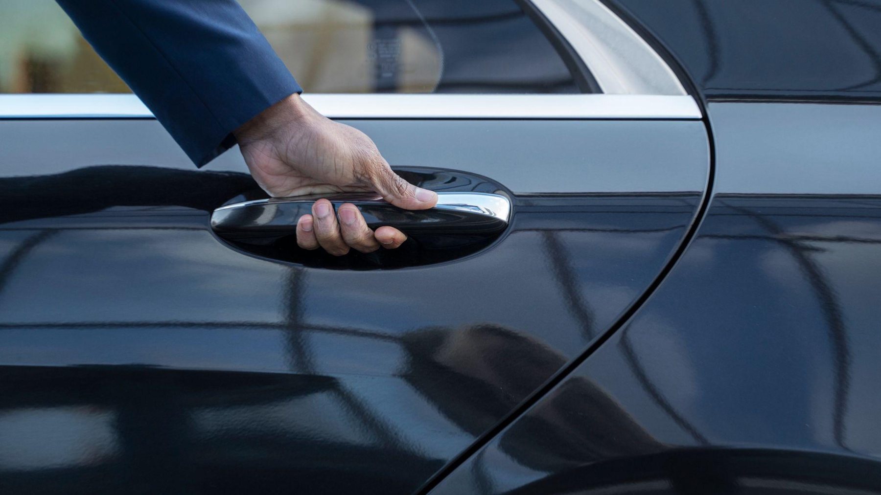 Hand öffnet die Tür eines Fahrzeugs