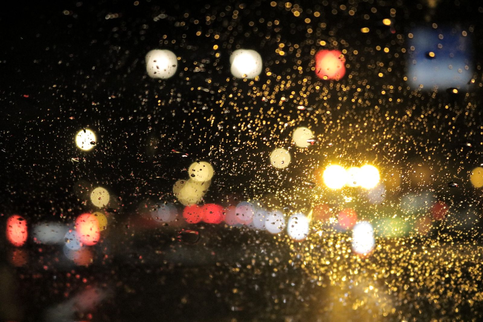 Regennasse Autoscheibe mit Lichtern bei Nacht